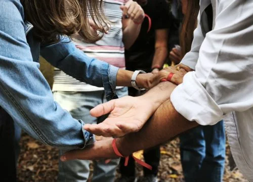 Equipa de colaboradores da empresa NOVO BANCO a darem as mãos para realizarem uma atividade de Team Building.